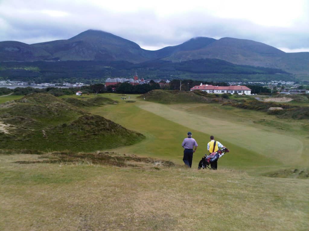 Golfer and caddie walking off the 9th tee at Royal County Down Golf Club