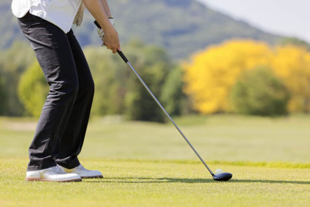 Amateur golfer hitting a hybrid club for their tee shot