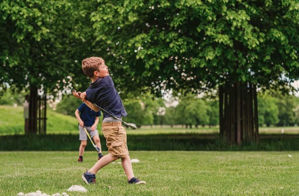 A young junior golfer following through after hitting a junior golf iron.