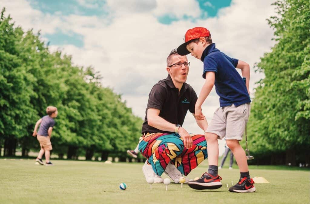 Andy Little, online golf coach, founder of Little Golfers and the first English PGA pro to earn U.S. Kids Golf Master Kids Coach status playing a fun putting game with a young golfer on the practice putting green